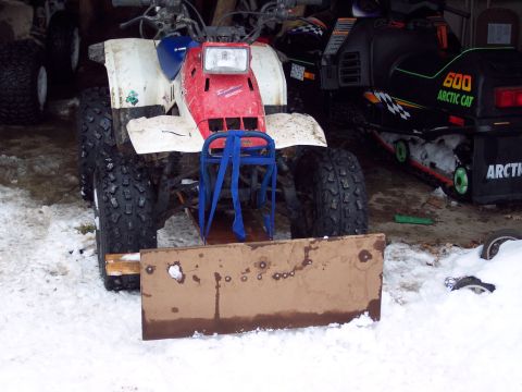 1987 Ford Bronco - An ATV equipped with a makeshift plow sits in the snow next to a snowmobile.