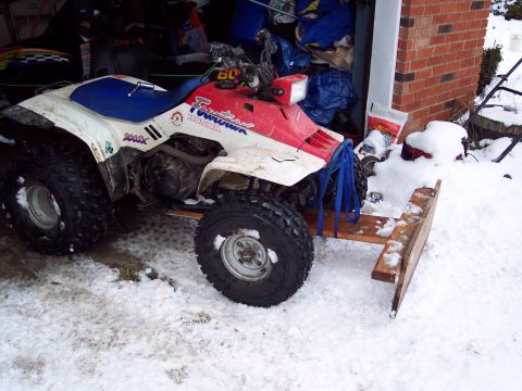 1987 Ford Bronco - A Honda FourTrax ATV is equipped with a rudimentary wooden snowplow, ready for winter conditions.