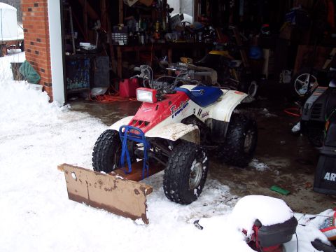 1987 Ford Bronco - ATV with a plow attachment sits in a garage during winter.