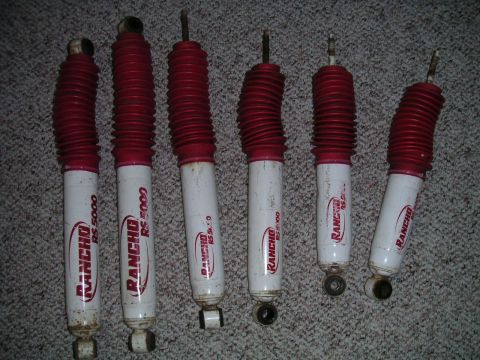 1994 Ford Bronco - Set of six Rancho RS 5000 shock absorbers, likely for a lifted vehicle, laid out on a carpeted surface.