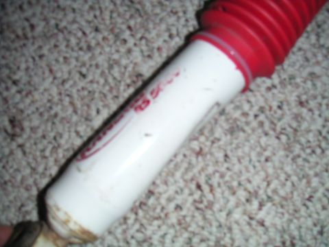 1994 Ford Bronco - A white and red shock absorber is shown against a carpeted background.