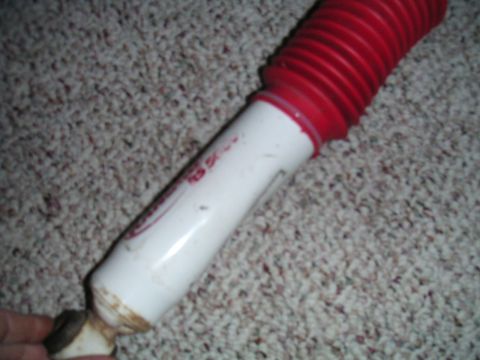 1994 Ford Bronco - A white shock absorber with a red boot and red lettering is shown against a carpeted background.