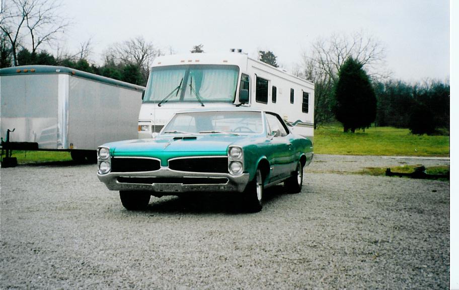Green 1967 Pontiac GTO parked in front of an RV and trailer