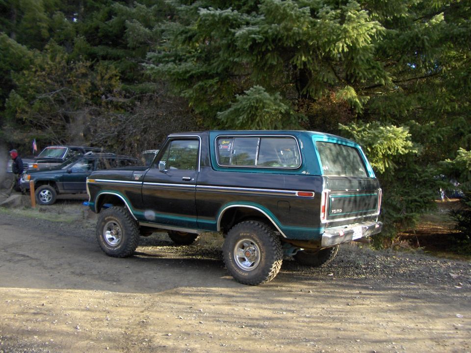 Black and teal 1978 Ford Bronco with lifted suspension and off-road tires, viewed from the rear three-quarter angle