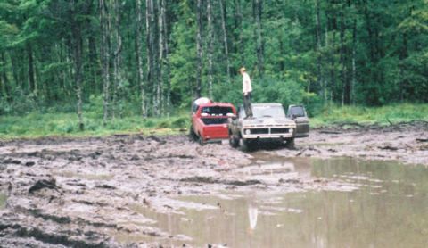 1977 Ford F-150 - A 1977 Ford F-150 and another truck are stuck in a muddy field, with a person standing on the hood of the F-150.