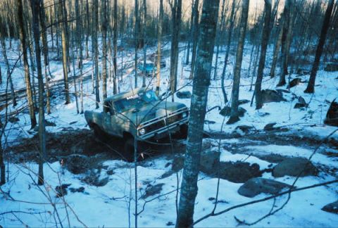 1977 Ford F-150 - Off-road truck stuck in mud and snow, with another vehicle visible further back on the trail.