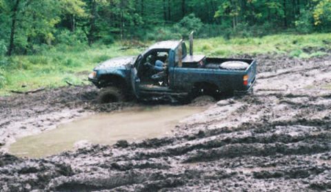 1977 Ford F-150 - This pickup truck is deeply stuck in a muddy off-road area, with its driver's side door open.