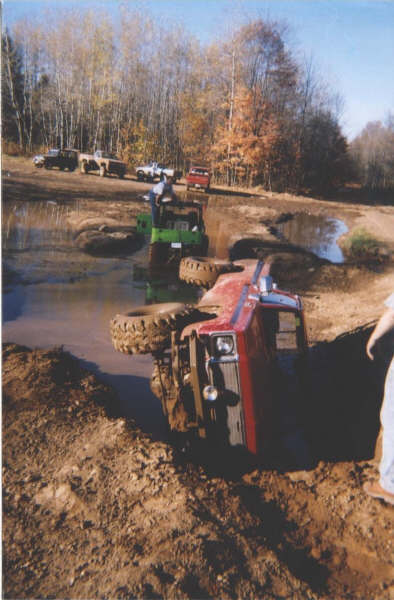 1977 Ford F-150 - Multiple vehicles stuck in a mud pit during an off-road event.