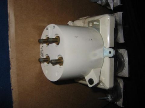 1985 Ford Bronco - A white cylindrical part with brass connectors is shown, possibly a component for a vehicle's electrical system.