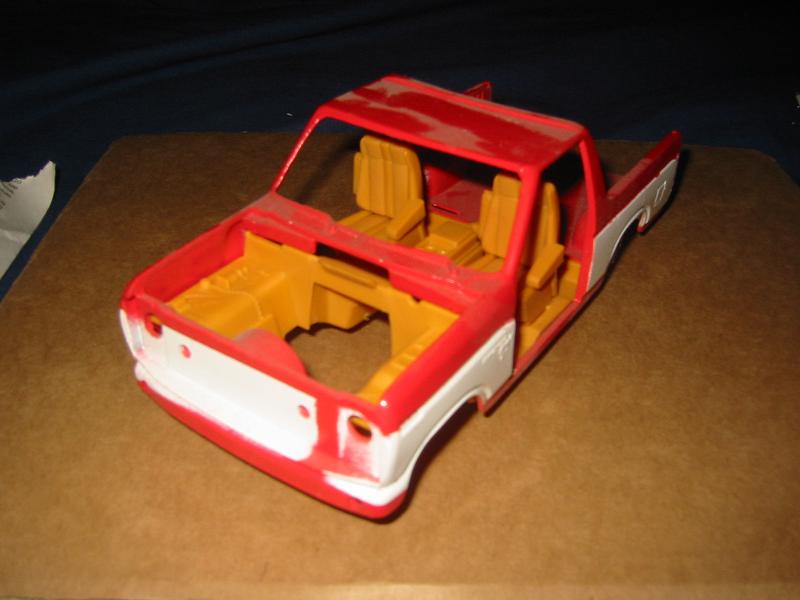 Red and white model truck body with yellow interior, viewed from a 3/4 front angle