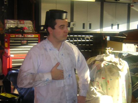 1992 Ford Crown Victoria - A man stands in a cluttered garage, wearing a peculiar hat and a stained shirt.