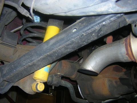 1992 Ford Crown Victoria - Close-up view of the rear suspension components, including a yellow shock absorber and exhaust system.