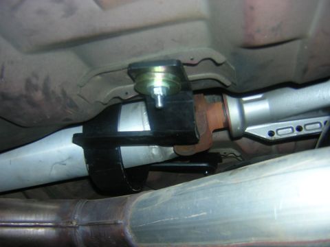 1992 Ford Crown Victoria - Underbody shot looking up at a driveshaft center support carrier bearing in its black bracket, bolted to the floorpan next to a gold-plated…