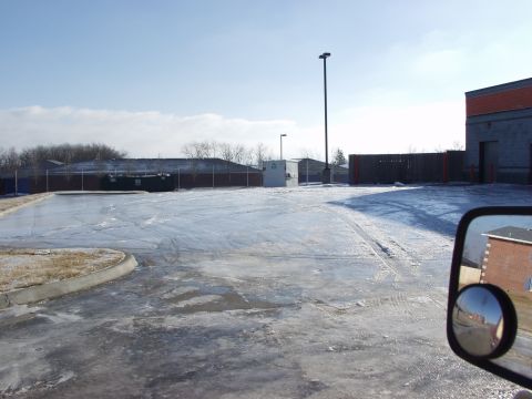 1979 Ford Bronco - A side mirror reflects a brick building and a street scene, with a snowy parking lot in the foreground.