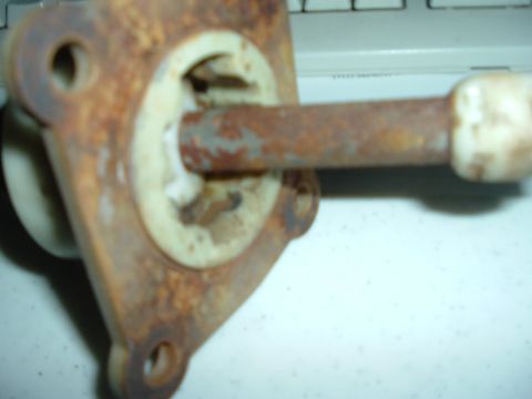1989 Ford Escort - A close-up view of a rusted metal component, possibly a shifter part, with a white knob and the Supermotors logo in the corner.