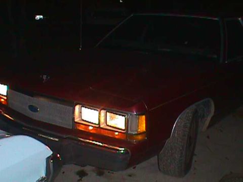 1994 Ford Crown Victoria - A red sedan is partially visible at night, with a white object obscuring the lower left corner.