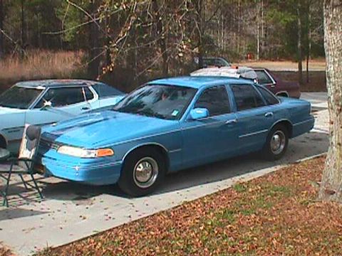 1994 Ford Crown Victoria - A blue 1994 Ford Crown Victoria is parked on a driveway next to another vehicle.