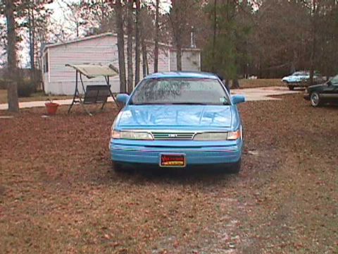 1994 Ford Crown Victoria - A blue sedan is parked in a yard with a mobile home and trees in the background.