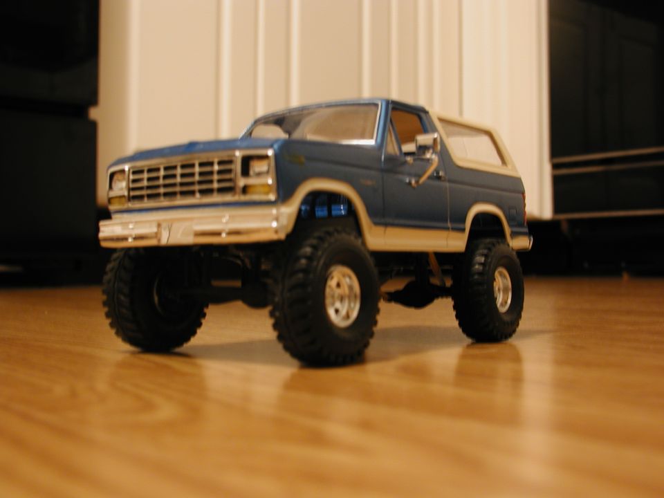 Blue and tan model SUV with large tires on a wooden floor