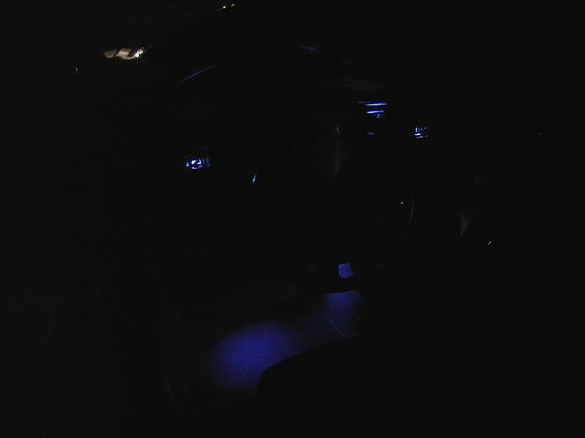 Car interior at night with blue footwell lighting visible