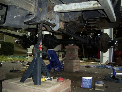 1995 Ford Bronco - Undercarriage of a vehicle undergoing repairs, supported by jack stands and bricks.