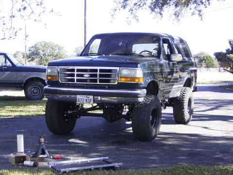 1995 Ford Bronco - A lifted 1995 Ford Bronco is parked outside, with another vehicle visible to the left.