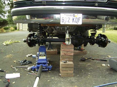 1995 Ford Bronco - Vehicle undergoing rear axle and suspension repair, supported by jacks and bricks.