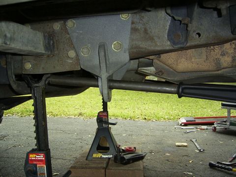1995 Ford Bronco - Vehicle is supported by jack stands, revealing its undercarriage and suspension system.