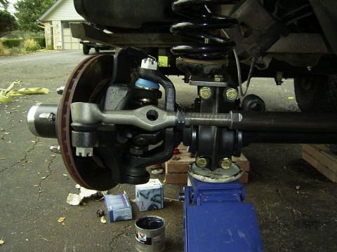 1995 Ford Bronco - Front suspension and steering components are visible, with a blue hydraulic jack supporting the vehicle's frame.