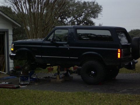 1995 Ford Bronco - A dark blue 1995 Ford Bronco is shown in profile, elevated on jack stands for maintenance.