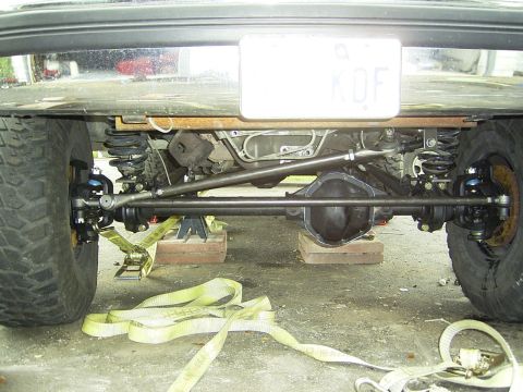 1995 Ford Bronco - The rear axle and suspension system of a vehicle are visible, raised on jack stands for maintenance.