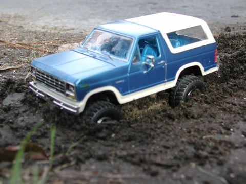 1985 Ford Bronco - This toy SUV appears to be stuck in a muddy environment, with its front grille clearly visible.