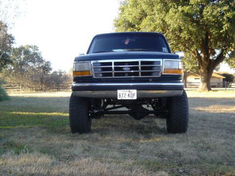 1995 Ford Bronco - This 1995 Ford Bronco features a prominent chrome grille and a lifted suspension, seen from a straight-on front view.