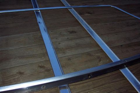 1985 Ford Crown Victoria LTD - Chrome trim pieces are laid out on a wooden floor, showing their construction and mounting points.