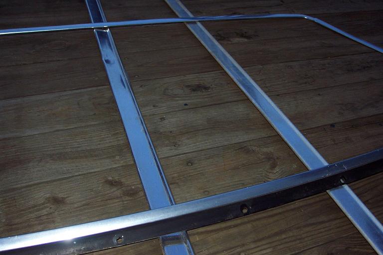 Chrome trim pieces with visible mounting holes on a wooden surface