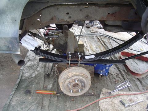 1990 Ford Bronco - Close-up view of the rear suspension and braking system of a vehicle, with tools present.