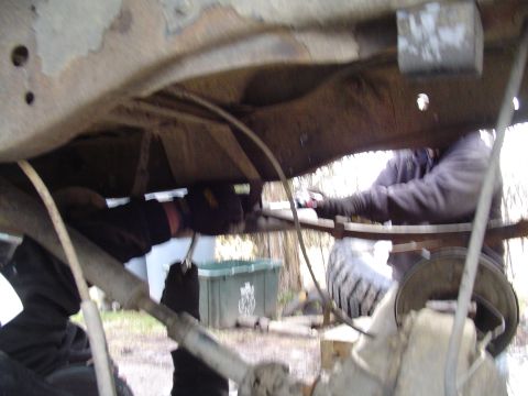 1990 Ford Bronco - Mechanics work on the suspension system of a vehicle, possibly during a lift installation.
