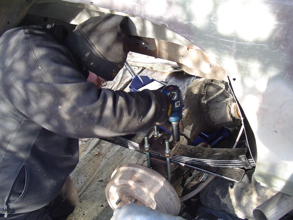 person working on leaf springs with impact wrench