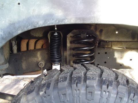 1990 Ford Bronco - A close-up view of the suspension system and tire of a vehicle, with visible text from SuperMotors.net.