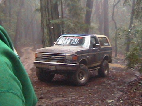 1990 Ford Bronco - Ford Bronco navigates a wet, wooded trail.