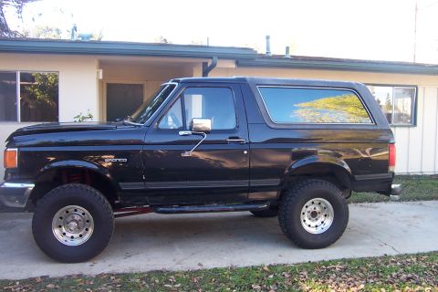 1989 Ford Bronco - This black 1989 Ford Bronco is seen from the side, parked in a driveway.