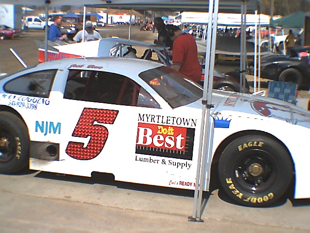 White number 5 stock car race car in side view at a racing paddock