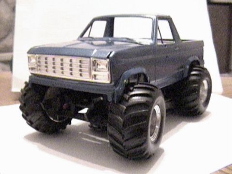 1979 Ford Bronco - Three-quarter front view of a scale plastic model of a lifted blue Ford Bronco built as a monster truck, with the top removed, a chrome egg…