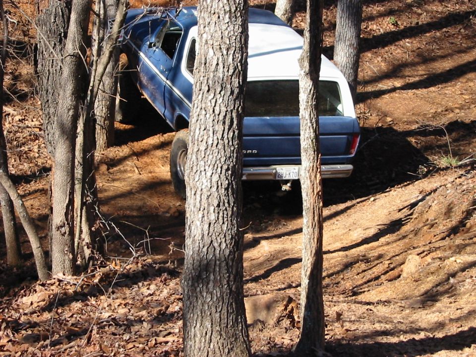 Blue and white 1978 Ford Bronco off-roading, rear view