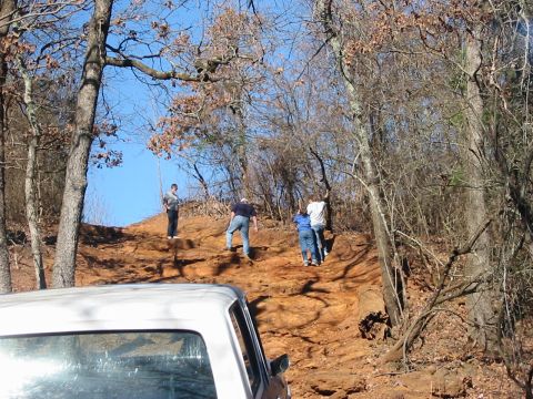 1978 Ford Bronco - A white pickup truck is partially visible in the foreground of a scene with people walking up a dirt hill.