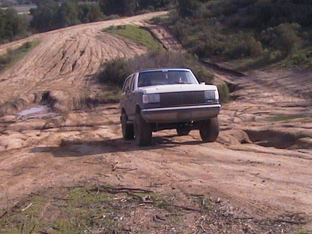 Two-tone SUV climbing a dirt off-road hill, front 3/4 view
