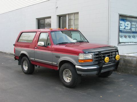 1995 Ford Bronco - This two-tone red and grey Ford Bronco features a brush guard with yellow smiley face fog lights.
