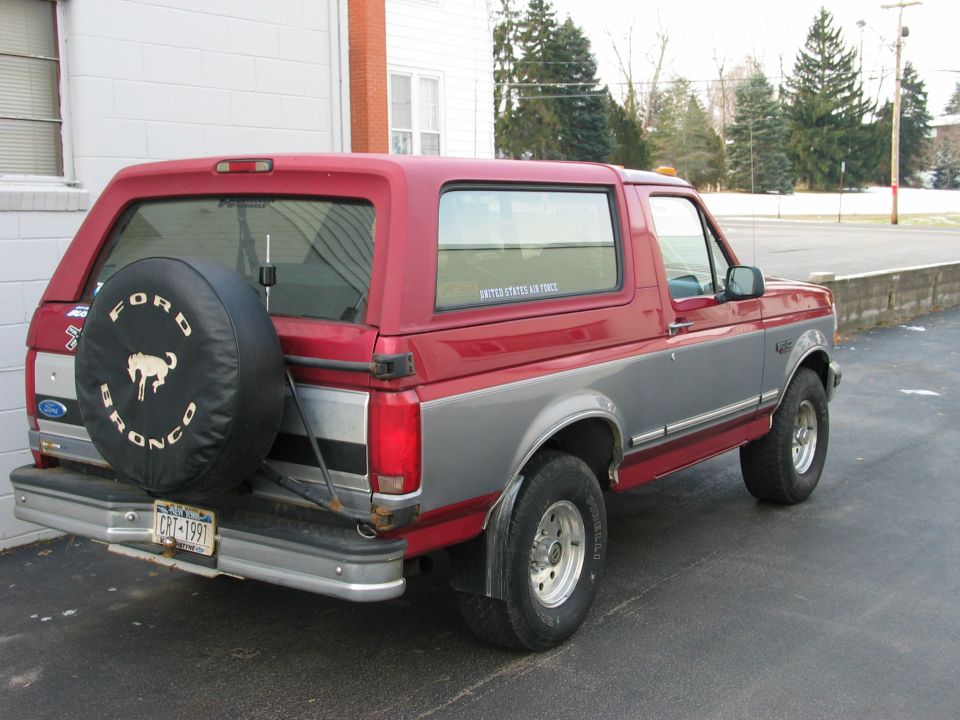 Red and gray Ford Bronco with spare tire on back. License plate reads CRT-1991
