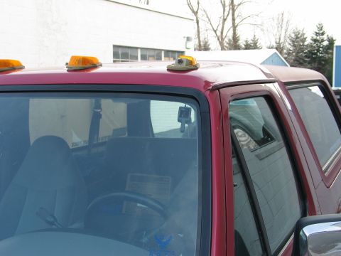 1995 Ford Bronco - Close-up view of the roofline and side window of a red SUV, amber clearance lights.