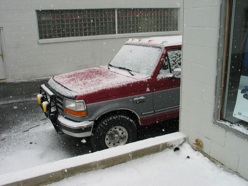 Red and gray pickup truck in snow, 3q-front view